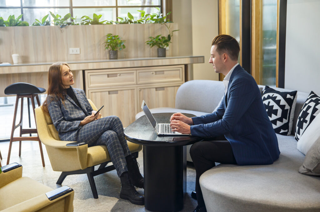 Two business professionals brainstorming in a more relaxed office setting.